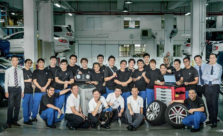 The Volkswagen aftersales service team photographed in their workshop with cars, tyres and tools.