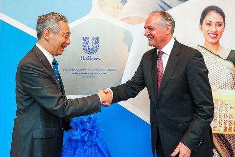 PM Lee and Paul Poulman shaking hands in front of a plaque indicating the official opening of Four Acres Singapore by Prime Minister Lee Hsien Loong, with a backdrop featuring the Unilever logo. Singapore corporate events photography for official opening ceremony.