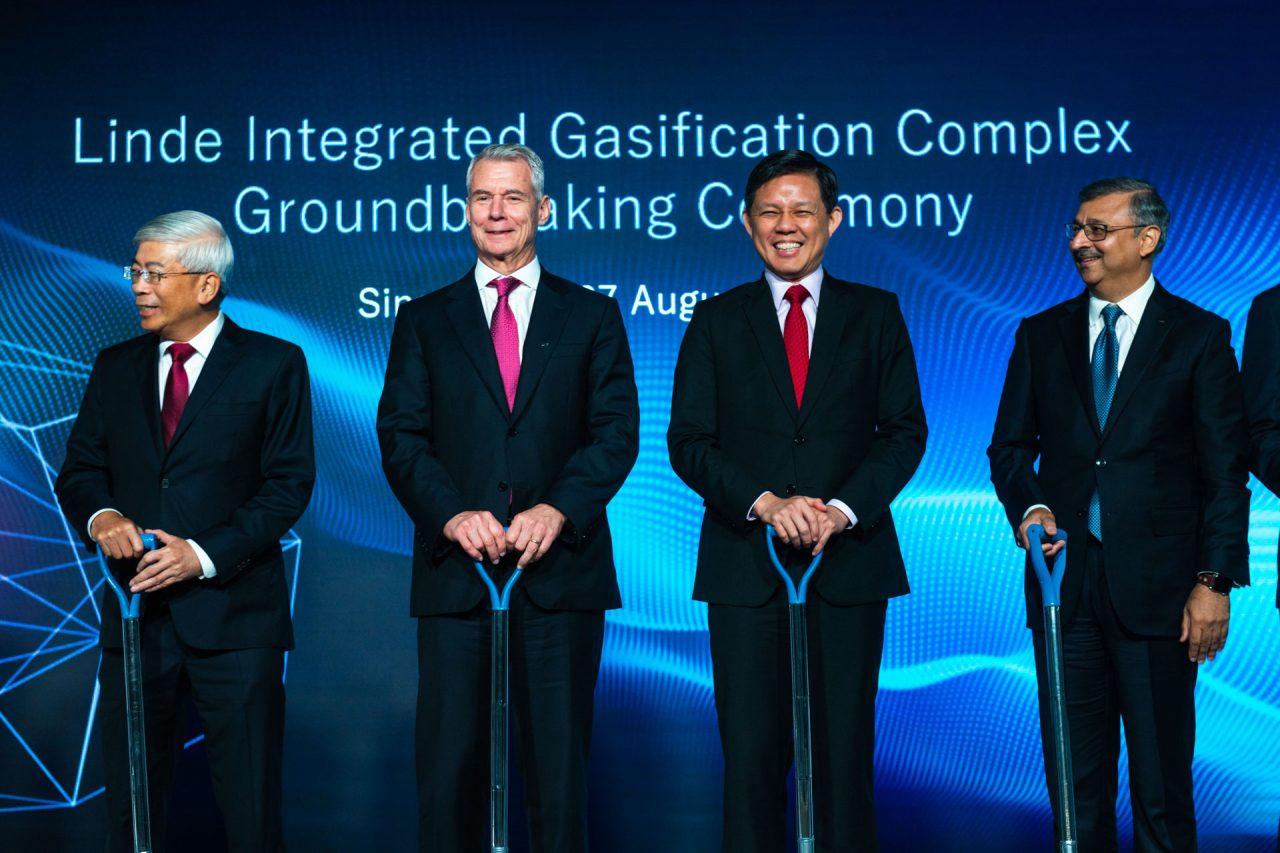 Four distinguished men in business suits holding shovels, standing in front of a backdrop that reads "Linde Integrated Gasification Complex Groundbreaking Ceremony, Singapore, 7 August." Singapore corporate events photography for official ground breaking events by Tucksy Photography