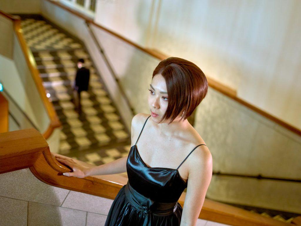 Publicity portrait for The Lost Lily, a woman in a black dress on the spiral staircase at National Gallery Singapore. professional photographer; advertising portraits; creative portrait photography; commercial portrait photography