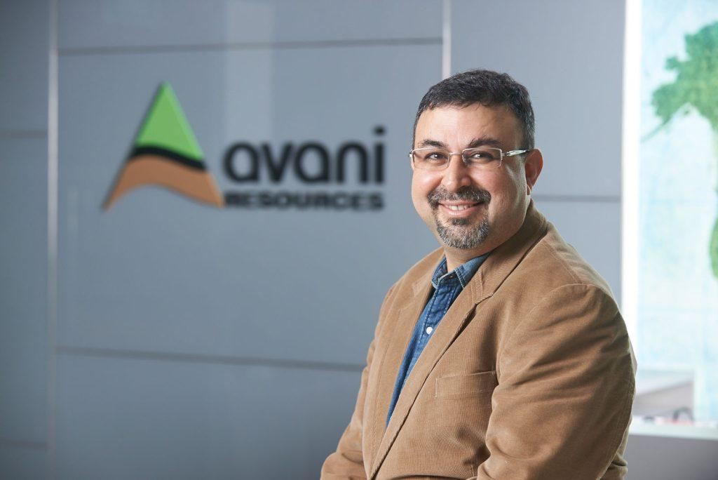Business headshot of Mr. Rajesh Johar of Avani Resources in front of the company logo, lit with studio lights