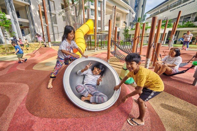Bespoke Playground 11 Group of children playing in a vibrant urban bespoke playground with modern apartments in the background. Lifestyle documentary photography