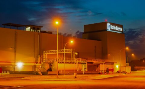 Rolls-Royce engine test bed building at Seletar, Singapore, at dusk, with fuel tanks and lamp posts lit against a deep blue sky