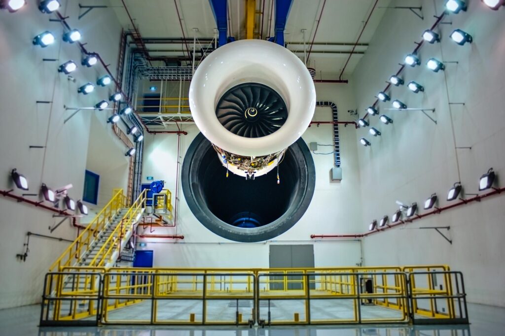 Trent engine hanging from an overhead cradle inside the Rolls-Royce Seletar test cell, floodlights on both walls and yellow railings below