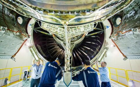 Technicians working beneath a turbofan inside the engine test cell. Aviation and aerospace photography in Singapore.