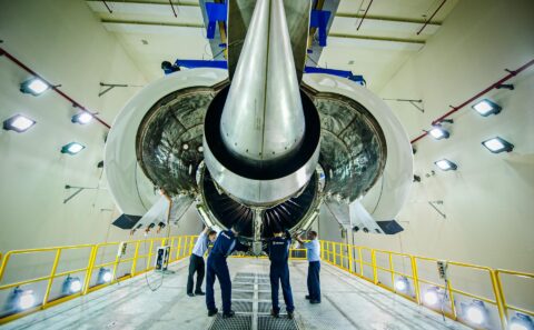 Technicians beside the engine intake inside the test cell, photographed as industrial interior work in Singapore.