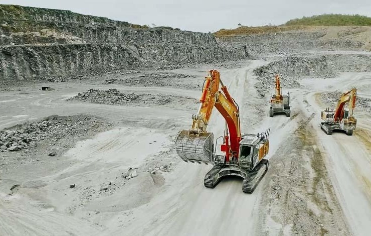 Three Hitachi ZX470 excavators working the floor of a stone quarry in Thailand, seen from the air with the quarry benches behind