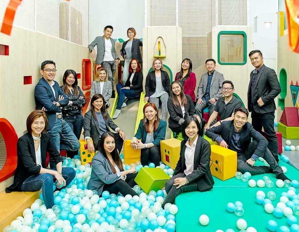 Creative team portrait photography: a Singapore sales team in business suits spread across the slides, cubes and ball pit of an indoor playground
